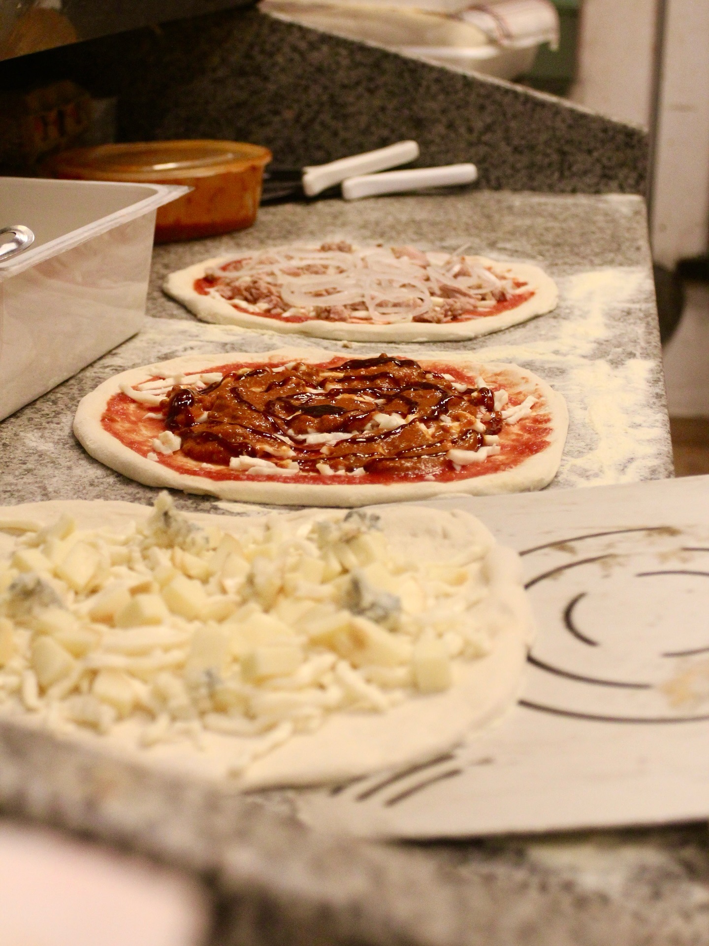 Two pizzas prepared side by side on a floured counter